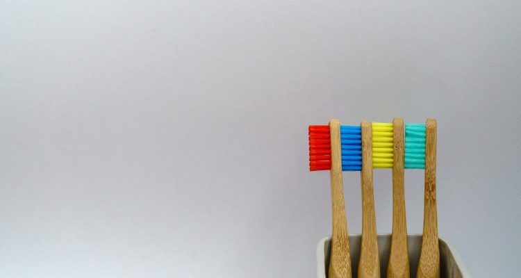 An image of a four toothbrushes with red, blue, yellow, and green bristles.