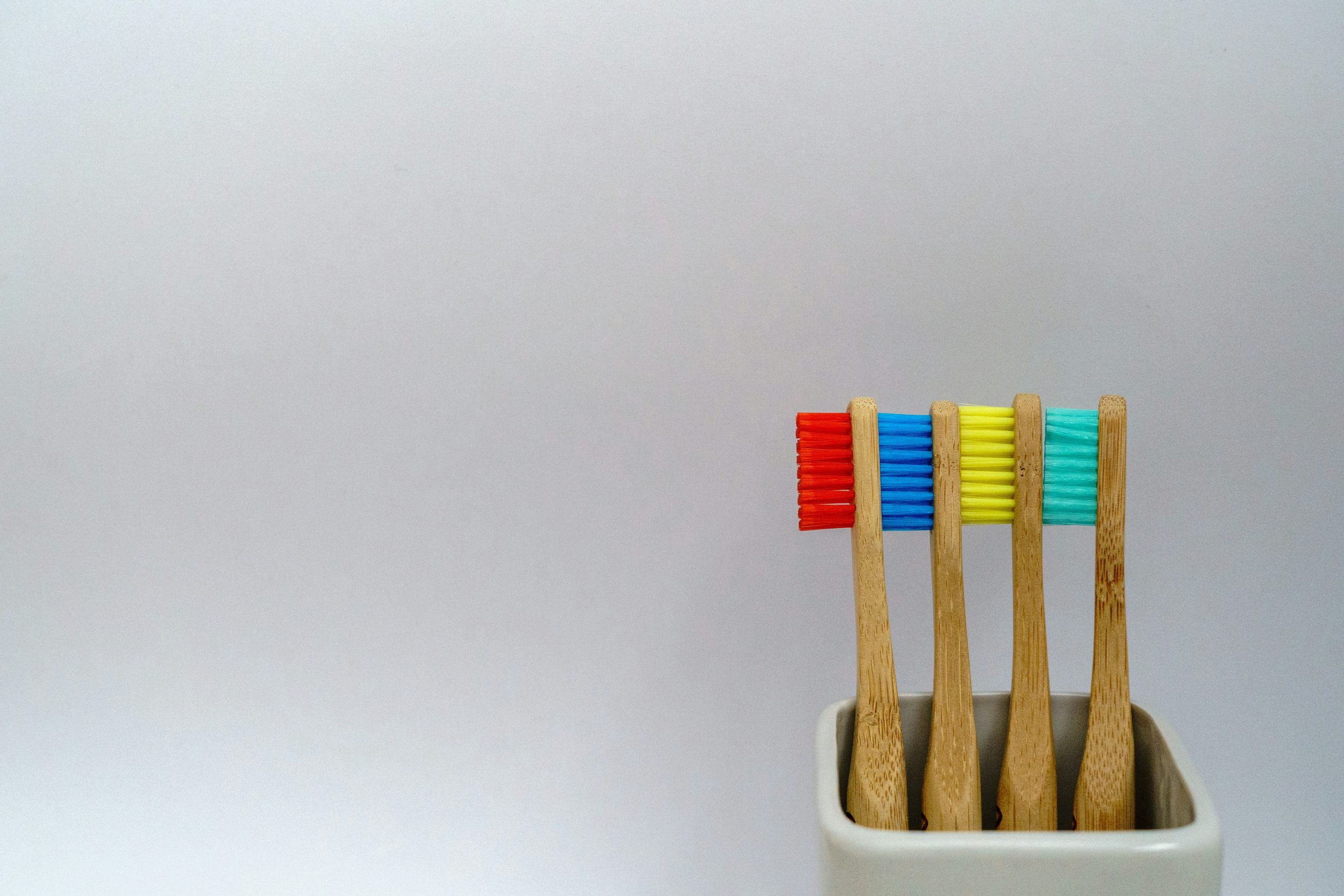 An image of a four toothbrushes with red, blue, yellow, and green bristles.