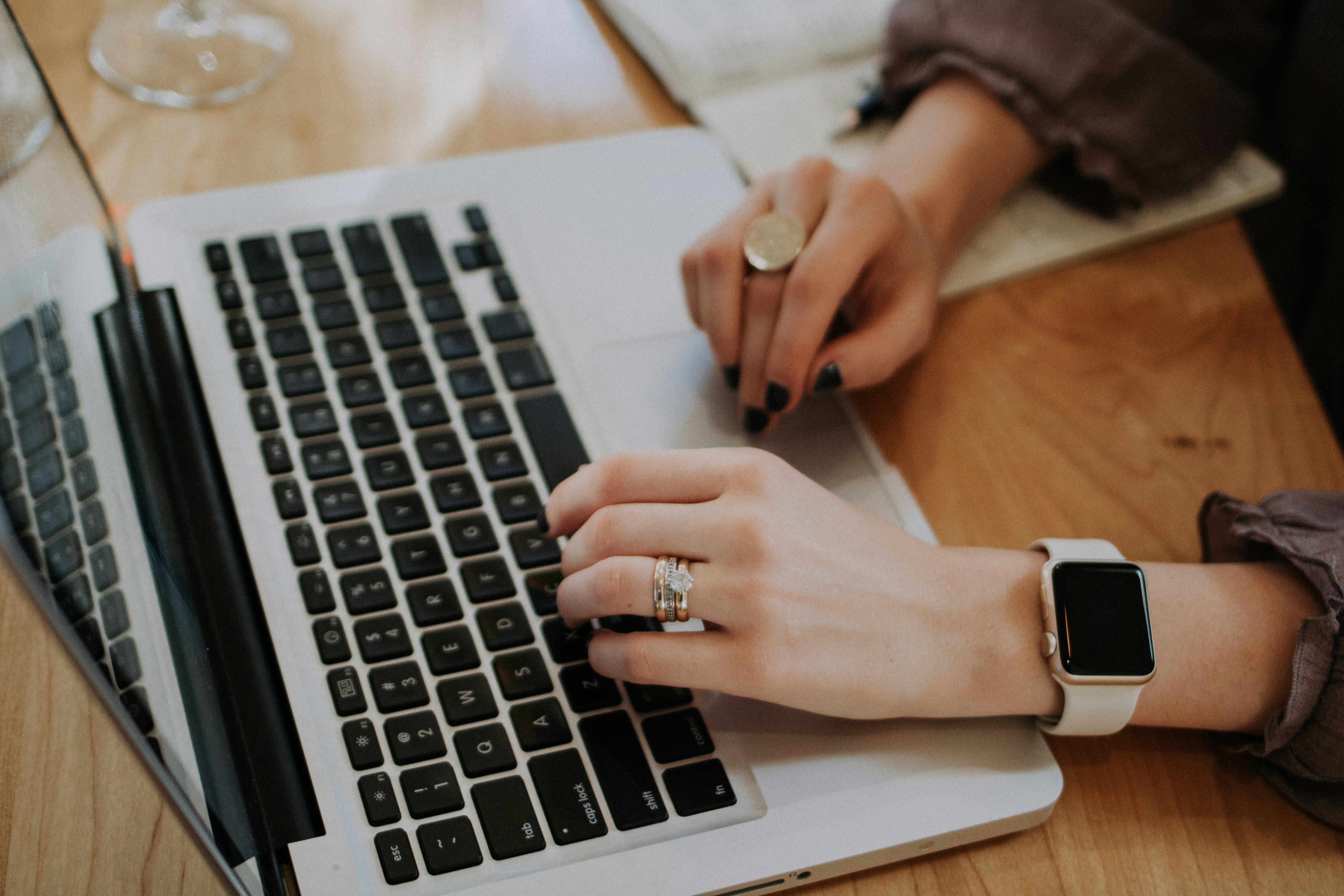 An image of a woman's hands typing website content with her laptop.