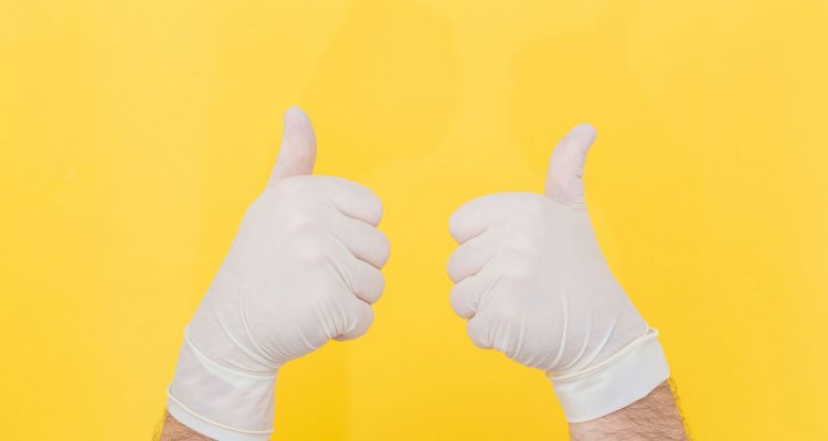 An image of hands wearing white gloves giving two thumbs up.