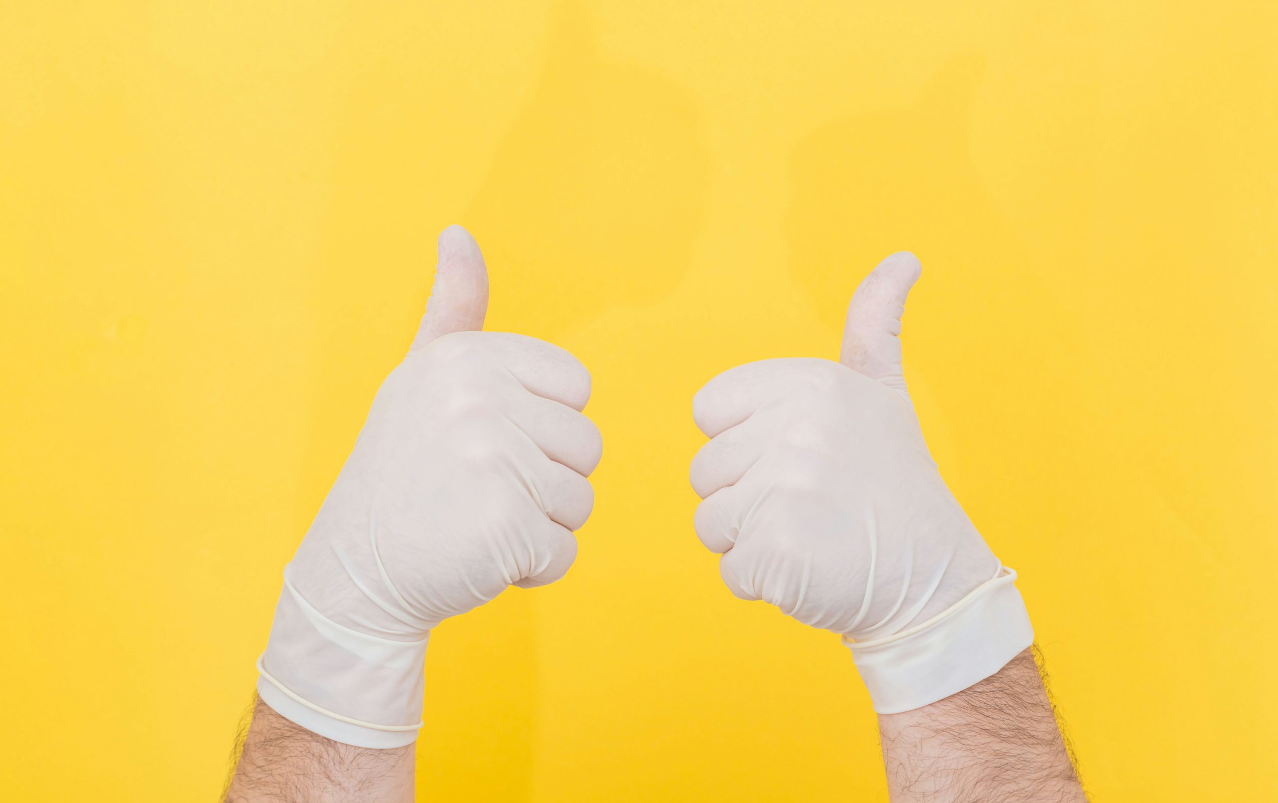 An image of hands wearing white gloves giving two thumbs up.