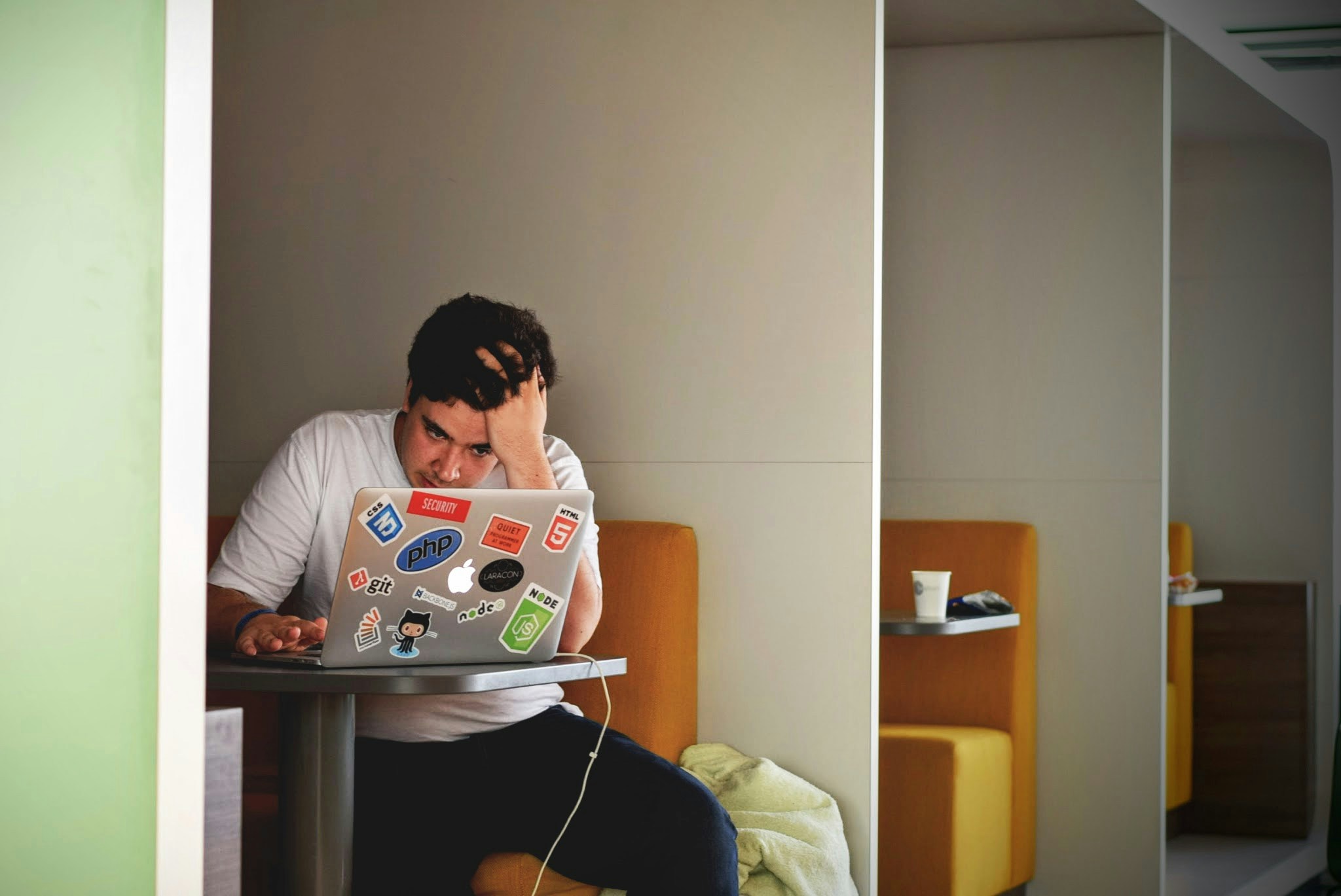 A man sitting in a table booth while on his laptop looks confused about changes to SEO.